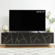 a flat screen tv sitting on top of a black entertainment center next to a white rug