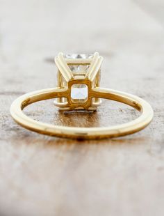 an engagement ring with a square cut diamond in the center on top of a wooden table