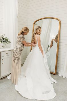 the bride is getting ready to go into her wedding dress in front of the mirror