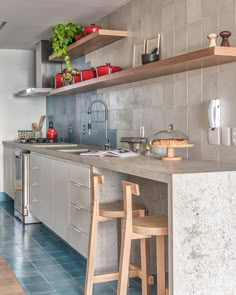 a kitchen with two stools next to a counter and shelves above the stove top