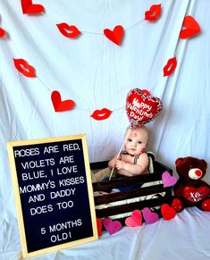 a baby sitting in a crate with hearts and a sign that says roses are red, violets are blue, i love mommy's kisses and daddy does too