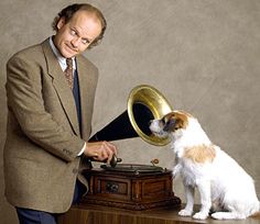 a man in a suit and tie is playing with a dog on a record player