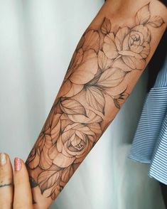 a woman's arm with flowers and leaves tattooed on the arm, in black and white