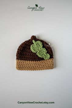 a crocheted beanie with a green leaf on the front and brown bottom