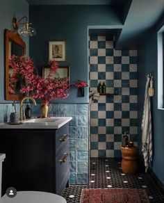 a bathroom with blue walls, black and white checkerboard flooring and a rug on the floor