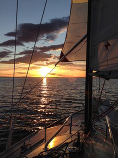 the sun is setting over the ocean on a sailboat