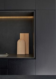 a wooden cutting board sitting on top of a counter next to a vase and bowl