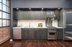 an empty kitchen with stainless steel appliances and wood floors