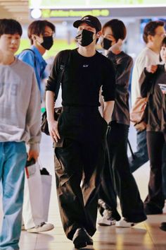 a man wearing a face mask while standing in front of other people at an airport