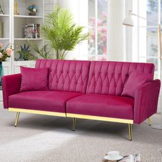 a pink couch sitting on top of a carpeted floor next to a book shelf