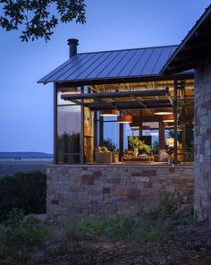 a house that is sitting on the side of a hill in the evening with its windows open