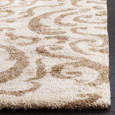 an area rug with brown and white designs on the floor in front of a wooden floor