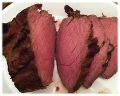 two pieces of meat sitting on top of a white plate next to another piece of meat