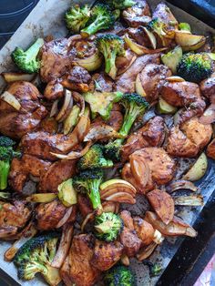 a tray filled with meat and vegetables on top of a table next to utensils