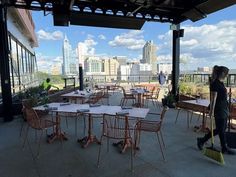 a woman sweeping the floor in front of an outdoor dining area with tables and chairs