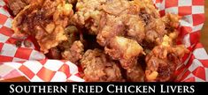 some fried chicken sitting in a basket on top of a wooden table with checkered paper