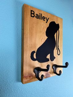 a wooden sign with a dog and leash hanging from it's side on a blue wall