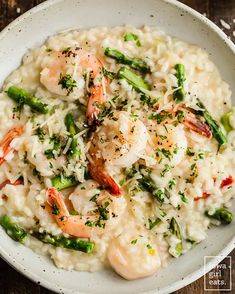 rice with shrimp and asparagus in a white bowl on a wooden table top