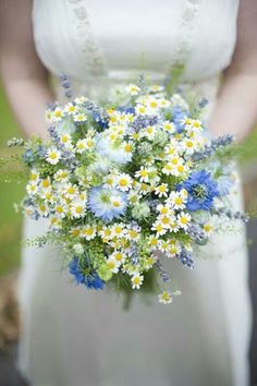 a woman holding a bouquet of daisies and blue flowers in her hands with the caption rockmyweddingphoto