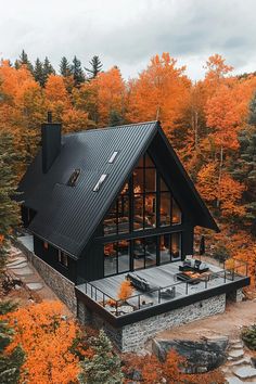 an aerial view of a house surrounded by trees with orange leaves in the fall season