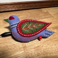 a small blue bird with red and green designs on it's body sitting on a wooden table