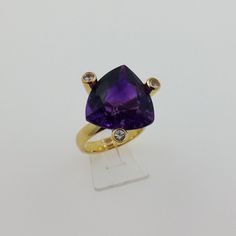 18k. Yellow gold ring with 1 Amethyst and 3 Sapphires total of 15.75 carat Triangle purple Amethyst & round Sapphires This unique ring handcrafted by use of 18k. yellow gold set with Triangle shaped natural Amethyst and white Sapphires total of 15.75 carat The earlier previously posted earrings have the same shape as the ring and can therefore as a set be worn Stones: natural quartz, variety amethyst & natural corundum, variety sapphire Shape and cut: triangle & round brilliant Carat weight: 4 - Round Sapphire, Yellow Gold Setting, 18k Yellow Gold Ring, Unique Ring, Yellow Gold Ring, Triangle Shape, Gold Set, White Sapphire, Purple Amethyst