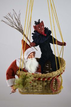 an ornament hanging from the ceiling with two puppets in it's basket