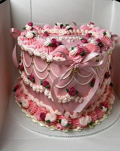 a large pink cake decorated with roses and ribbons