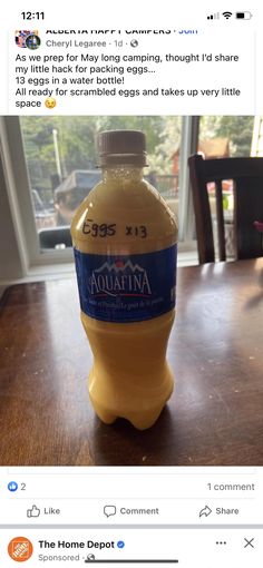 a bottle of orange juice sitting on top of a wooden table next to a window