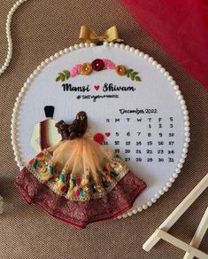 a cross stitch ornament with a dress and hat on it next to some knitting needles