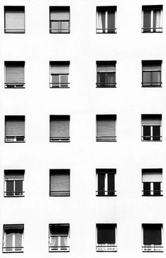 several windows with arabic writing on them in front of a white building that has many windows