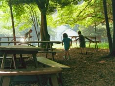 two children are playing in the woods near picnic tables