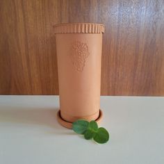 a cup with some green leaves on the table