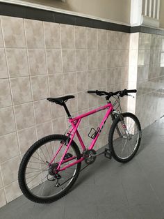 a pink bike parked in front of a tiled wall