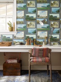 a desk with a chair and many pictures on the wall behind it in front of a window