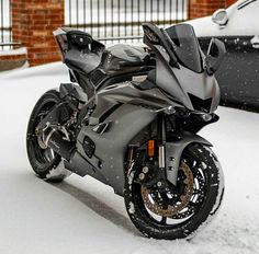 a motorcycle parked in the snow next to a car