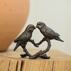 two metal birds sitting on top of a tree branch