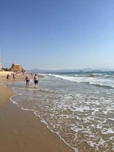 people are walking along the beach near the water