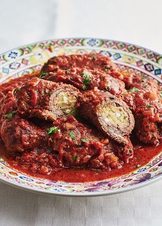 meatballs covered in marinara sauce and parsley on a colorful plate with white tablecloth