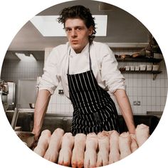 a man in an apron standing behind some chicken feet on a table with other meats