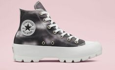 a pair of black and white converse sneakers on a pink background with space for text