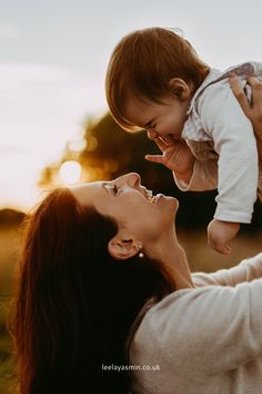 a woman holding a baby up in the air