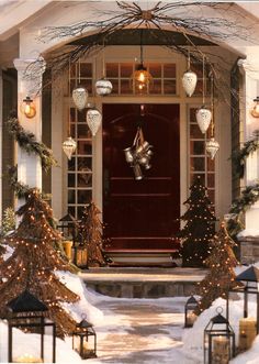 the front door is decorated for christmas with lights and garlands on the trees outside