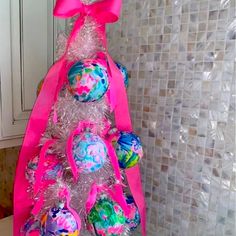 a christmas tree made out of plastic balls with pink ribbon and bows on the top