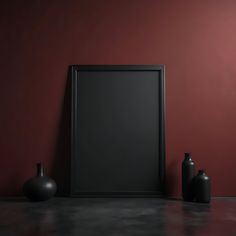 two black vases and a framed photograph on a table against a red wall in front of it