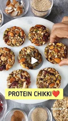 a white plate topped with cookies and nuts next to bowls filled with different kinds of food