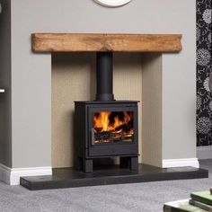 a wood burning stove in a living room next to a table and clock on the wall