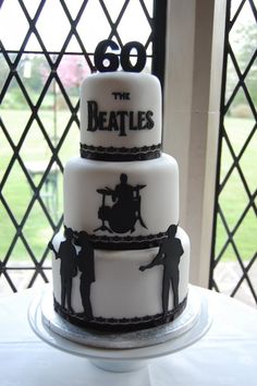 a three tiered cake sitting on top of a white table next to a window