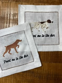 two embroidered napkins with dogs on them, one is brown and the other is white