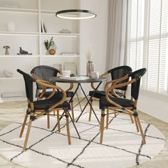 two black chairs sitting at a round table in front of a white bookcase and window